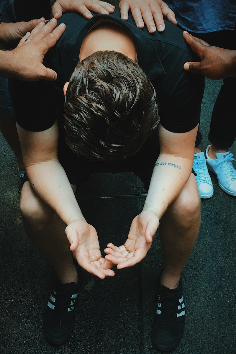 man sitting on chair holding and surrounded by people praying. Don't count Him out.