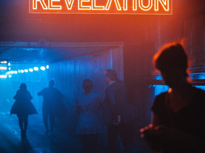 a group of people standing under a neon sign