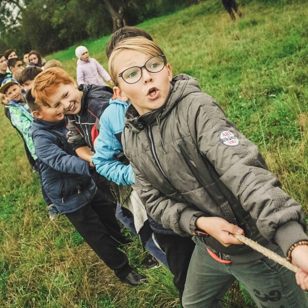 group of children pulling brown rope showing how Teamwork makes the dream work