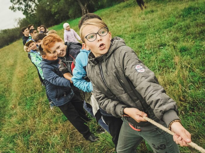 group of children pulling brown rope showing how Teamwork makes the dream work