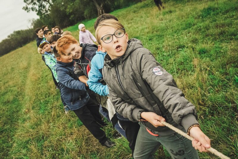 group of children pulling brown rope showing how Teamwork makes the dream work